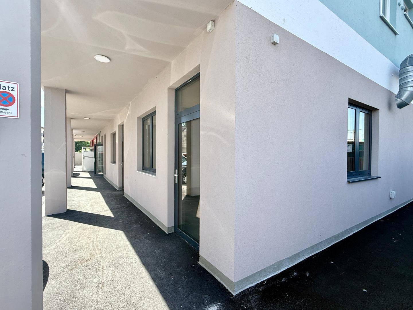 Überdachter Außenbereich mit Säulen und Fenstern einer Gewerbefläche in einem Neubau.