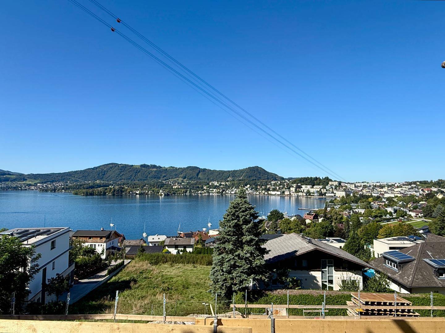 Weitblick über einen See, Berge und eine Stadt von einer Baustelle aus.
