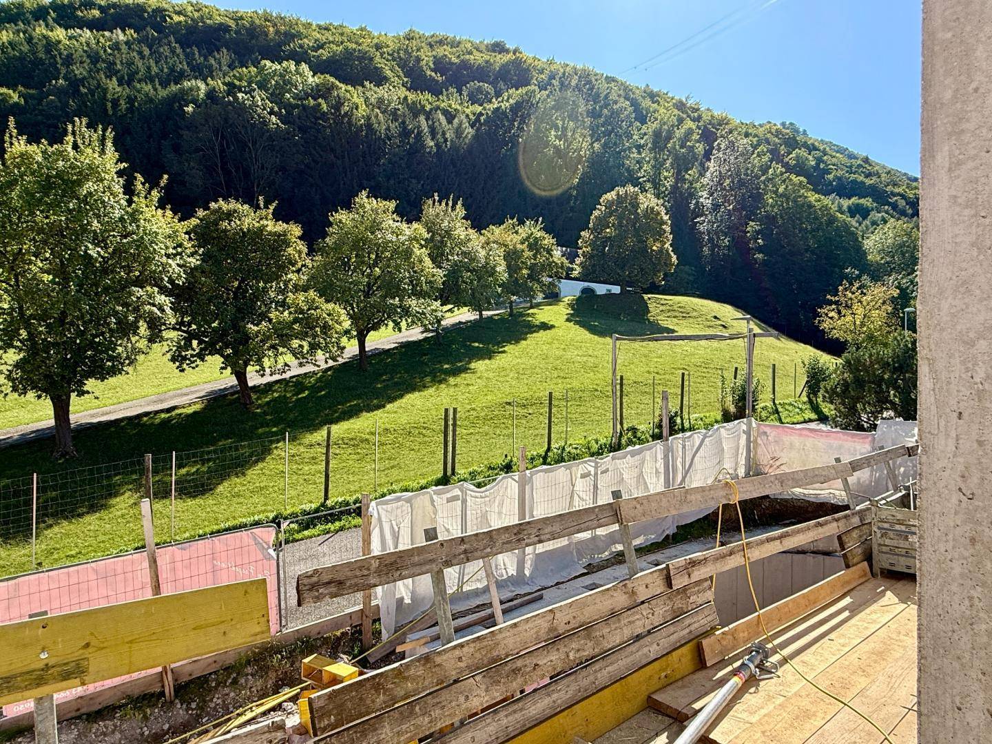 Blick auf eine grüne Hügellandschaft von einer Baustelle aus.