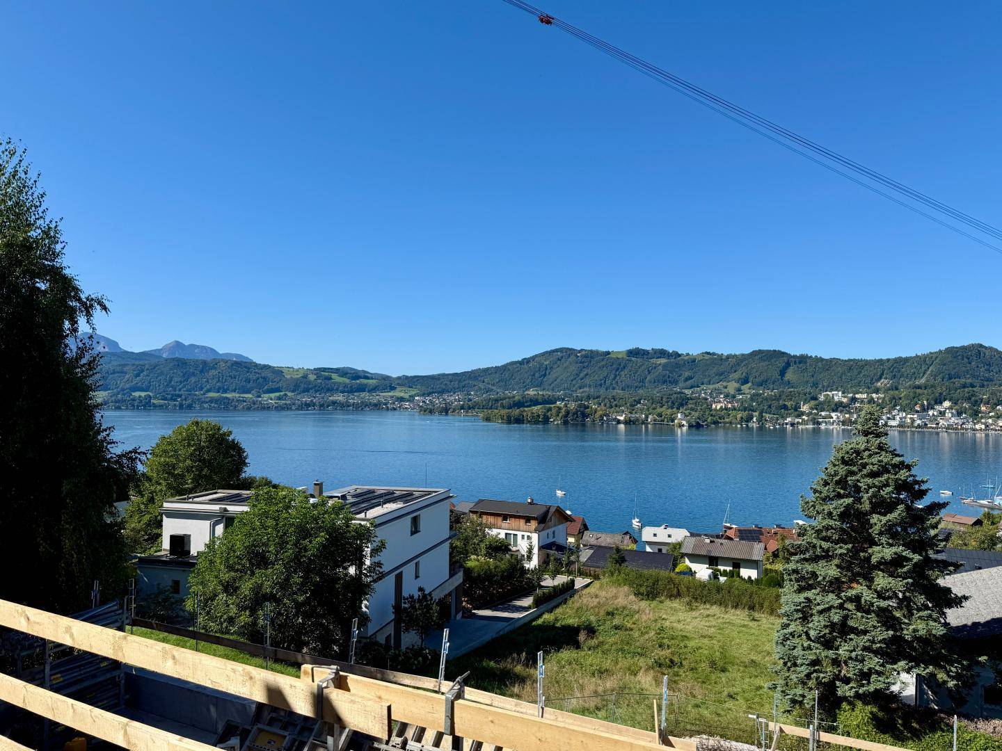 Panoramablick auf einen See und Berge von einer Baustelle unter blauem Himmel.