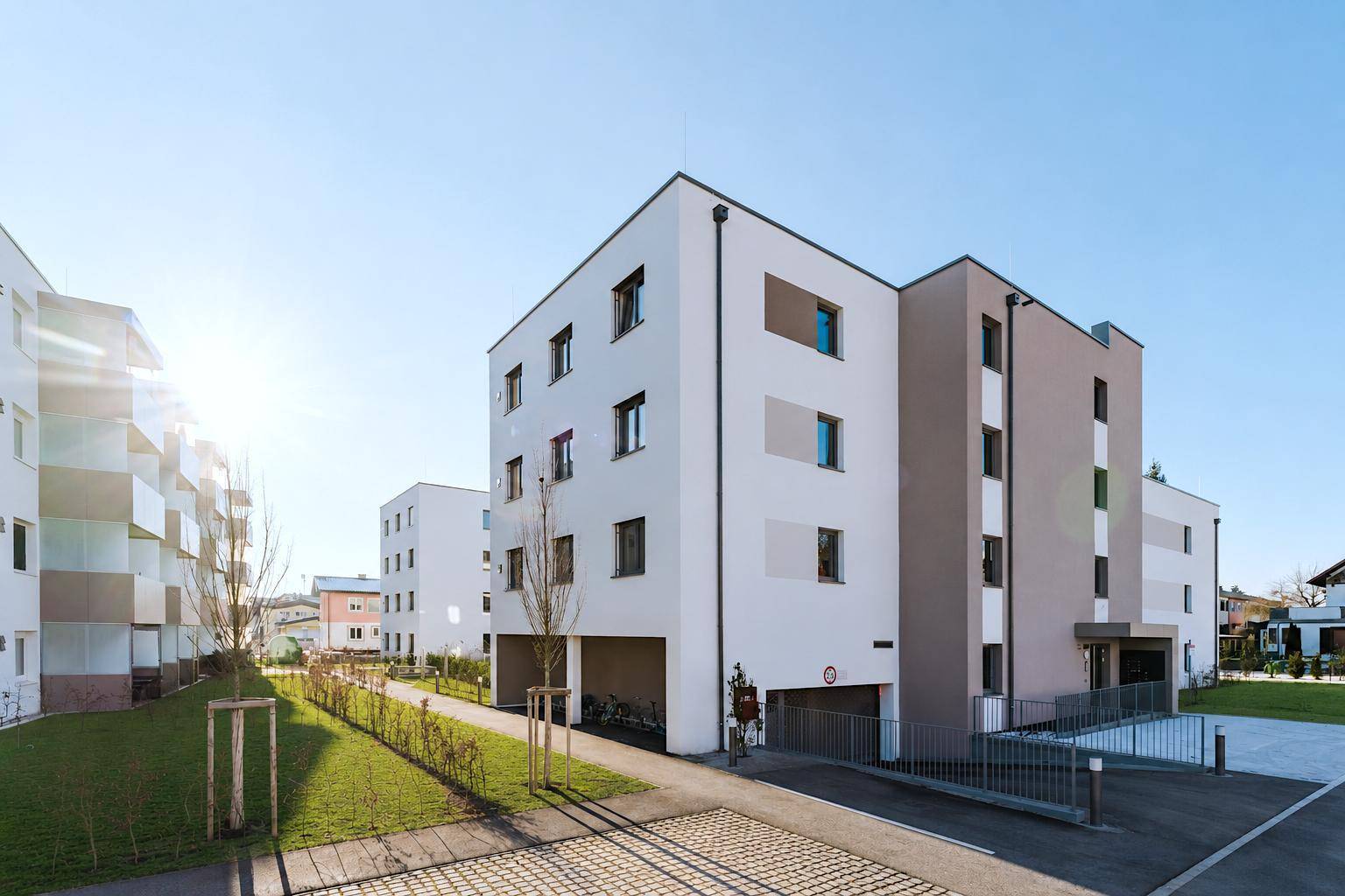 Moderne Wohnanlage mit ansprechender Fassadengestaltung, Tiefgaragenzufahrt und Grünflächen.