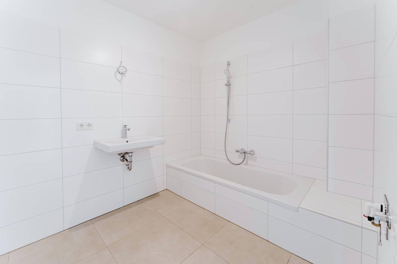 Modernes Badezimmer mit weißen Fliesen, Badewanne und Waschbecken, bereit zur Fertigstellung.
