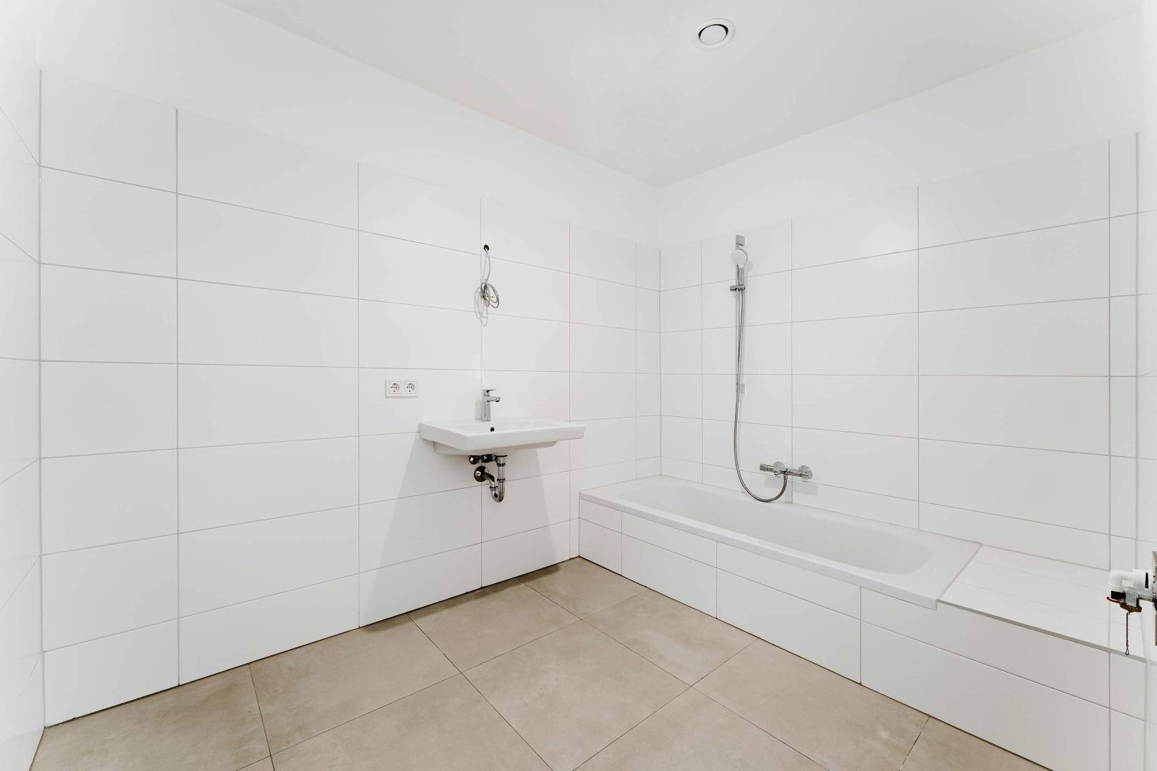 Modernes Badezimmer mit weißen Fliesen, Badewanne und Waschbecken.