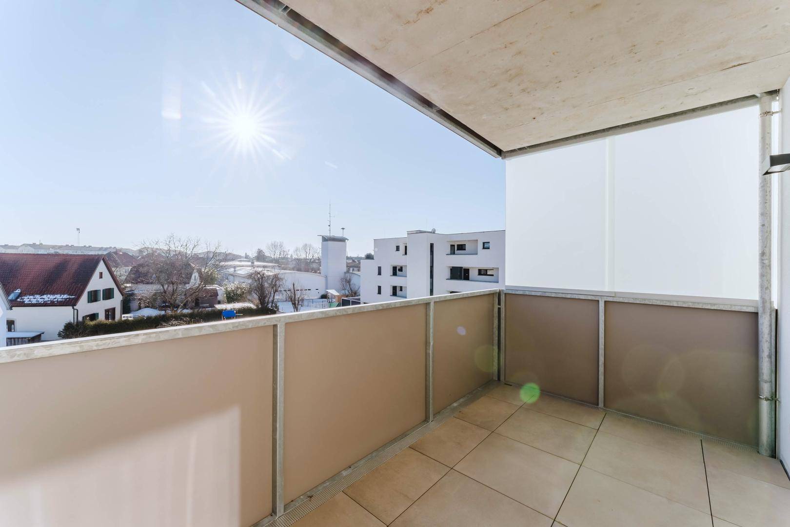 Heller Balkon mit Fliesenboden und weitem Blick über die Umgebung.
