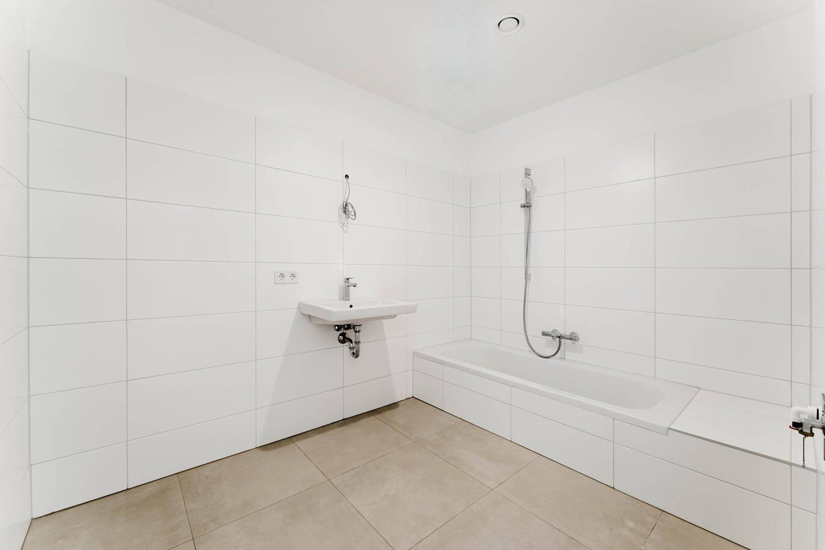 Modernes Badezimmer mit weißen Fliesen, Badewanne und einem einzelnen Waschbecken.