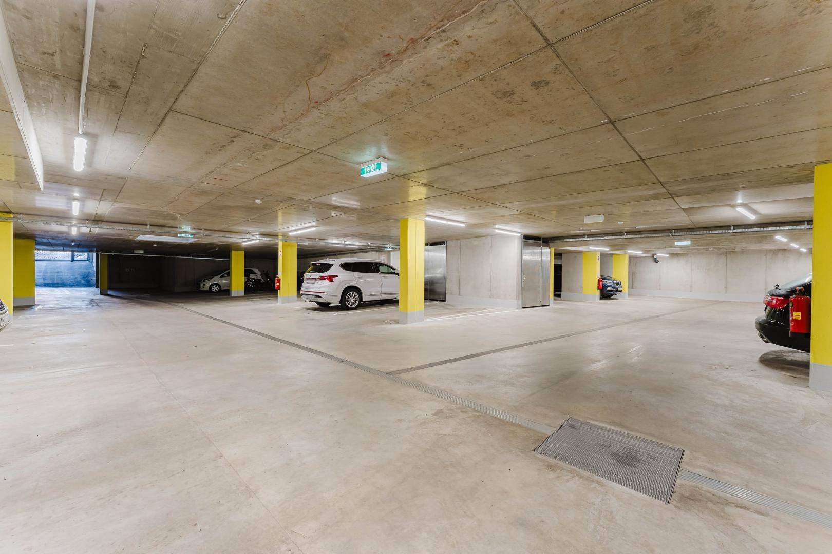 Geräumige Tiefgarage mit Betonboden und gelben Säulen für Bewohnerfahrzeuge.