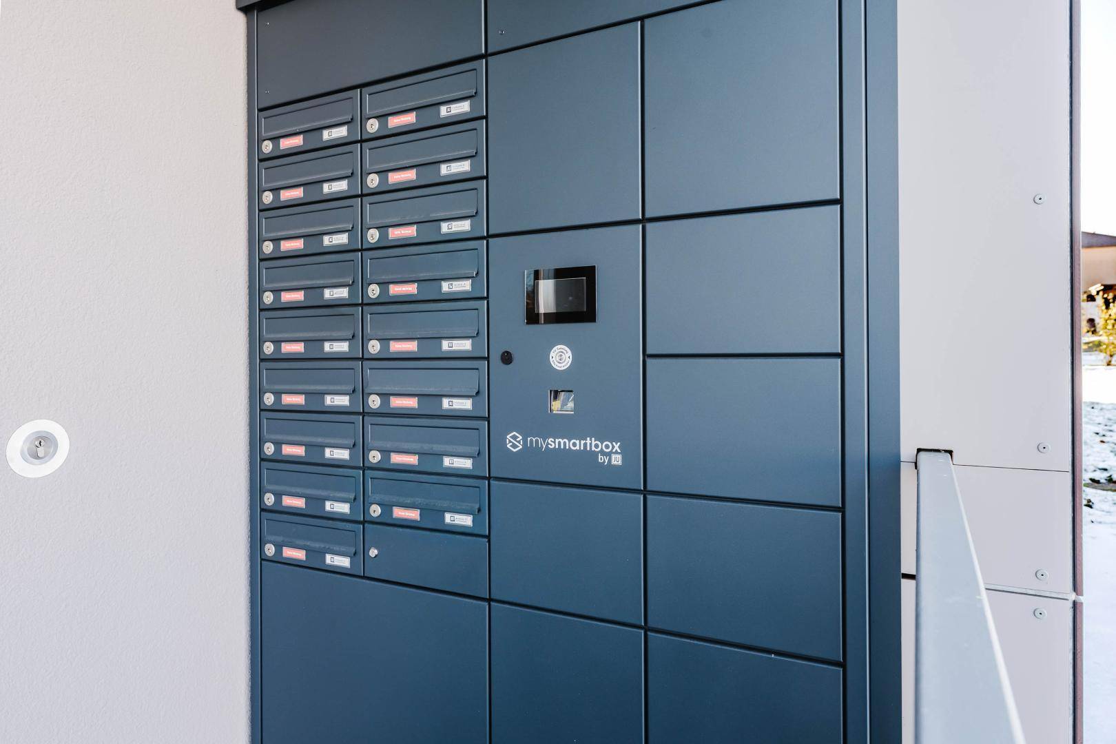 Moderne Briefkastenanlage mit Paketboxen im Eingangsbereich eines Wohngebäudes.