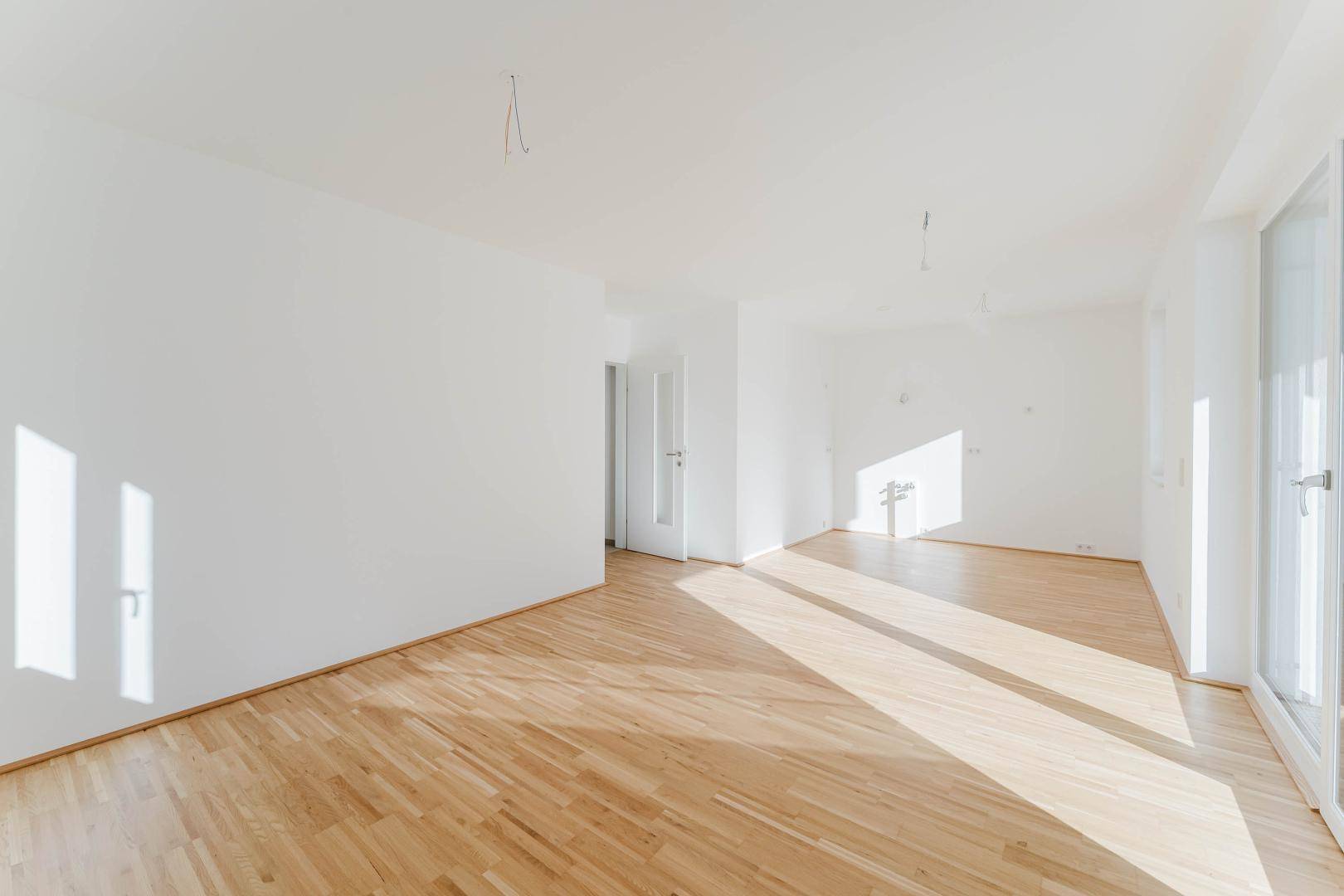 Geräumiger, heller Wohnraum mit Parkettboden und weiß gestrichenen Wänden, bereit zur individuellen Gestaltung.