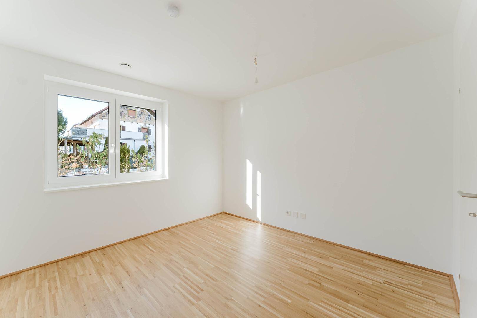 Geräumiges Schlafzimmer mit hellem Parkettboden und weiß gestrichenen Wänden, ideal für individuelle Einrichtung.