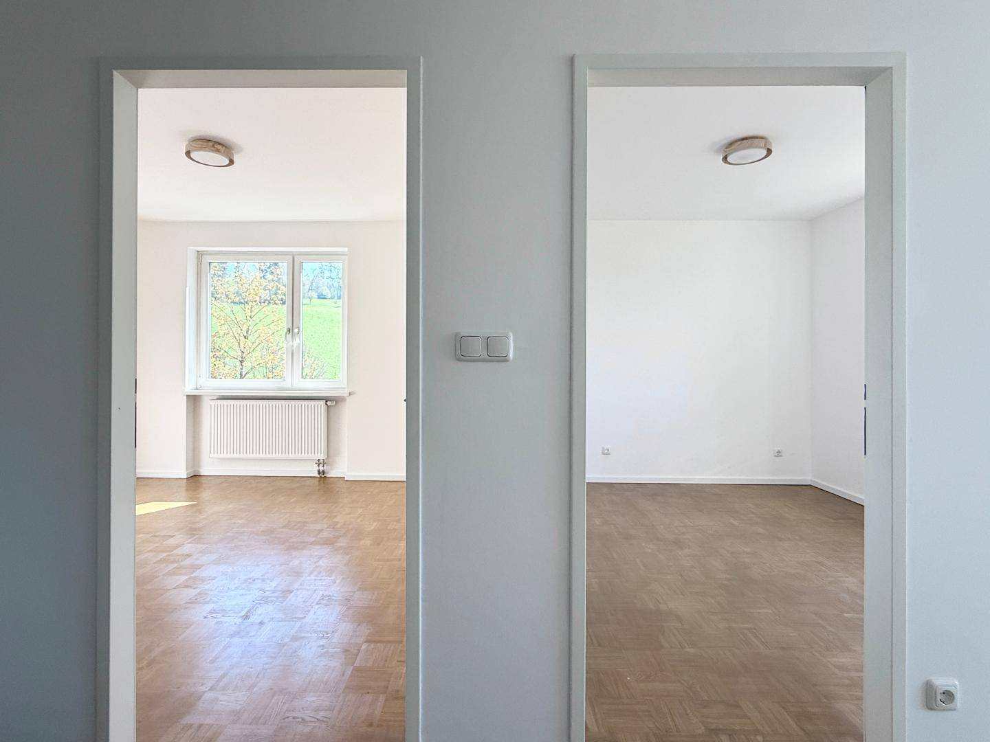 Blick durch zwei Türöffnungen in helle, unmöblierte Zimmer mit Parkettboden.