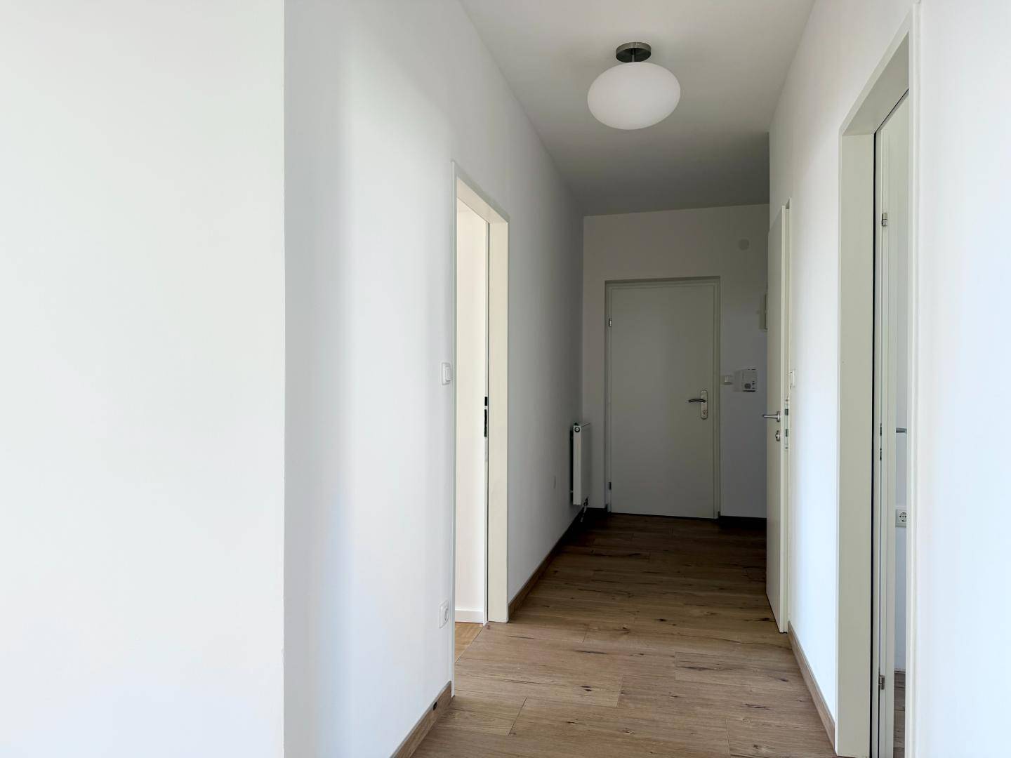 Langer, heller Flur mit Holzboden und Türen, die zu den verschiedenen Räumen führen.