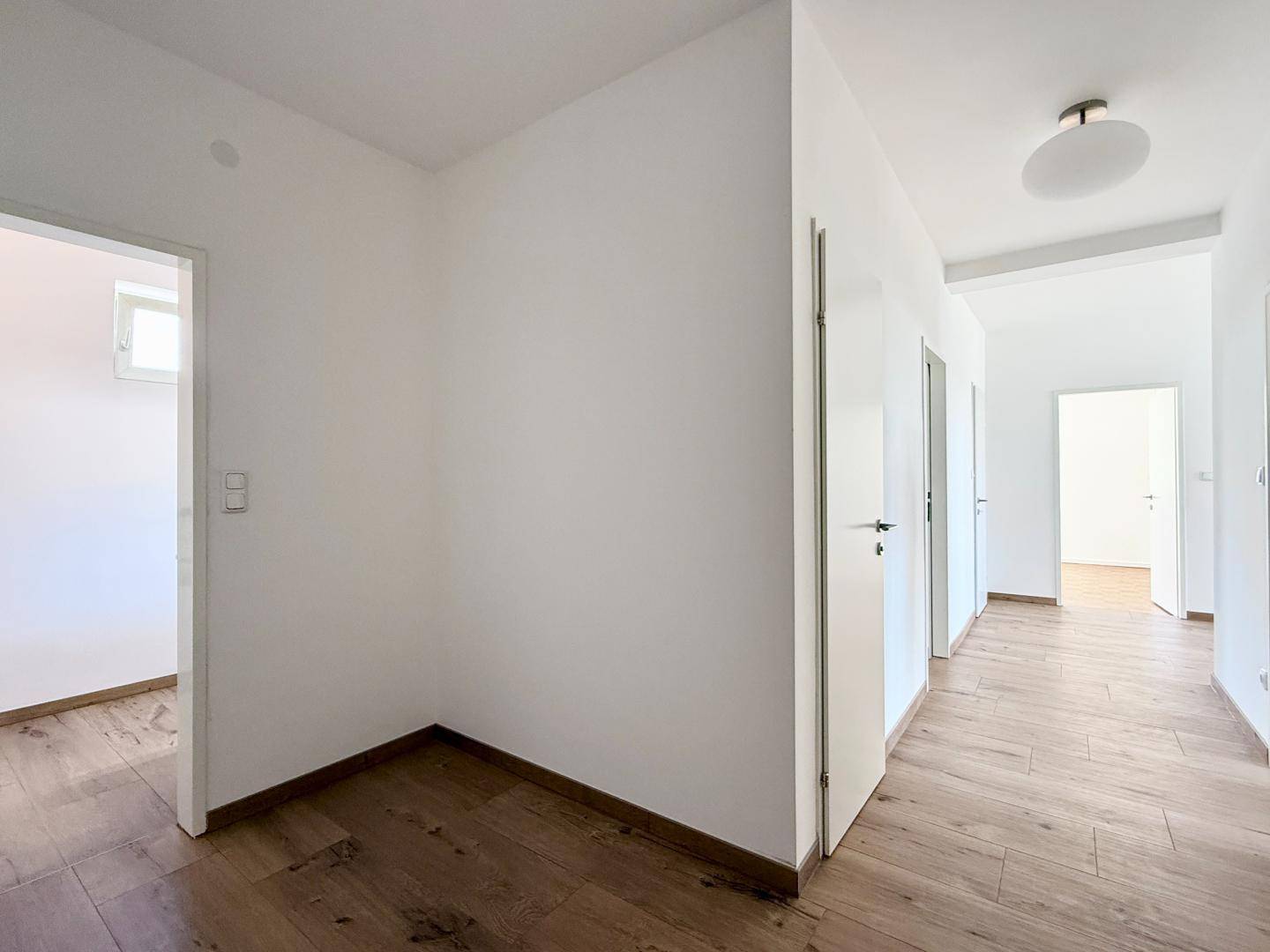 Heller Flur mit Holzboden und mehreren Türen, die zu den angrenzenden Zimmern führen.