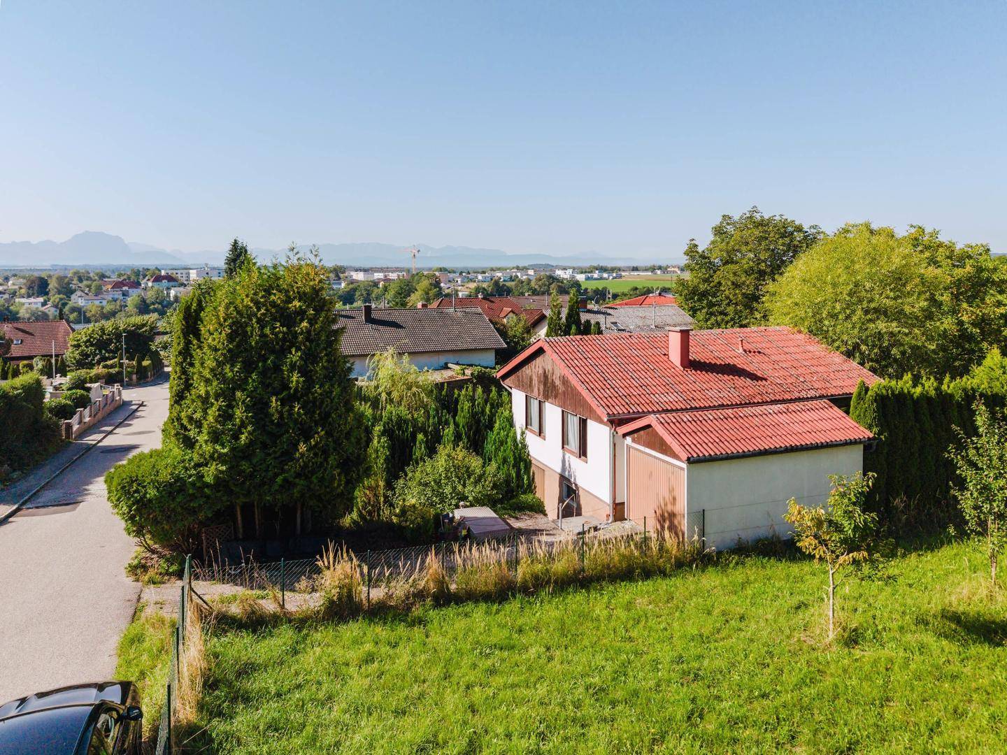 Luftaufnahme des Hauses mit rotem Dach, umgeben von Grünflächen und einer Wohnstraße.