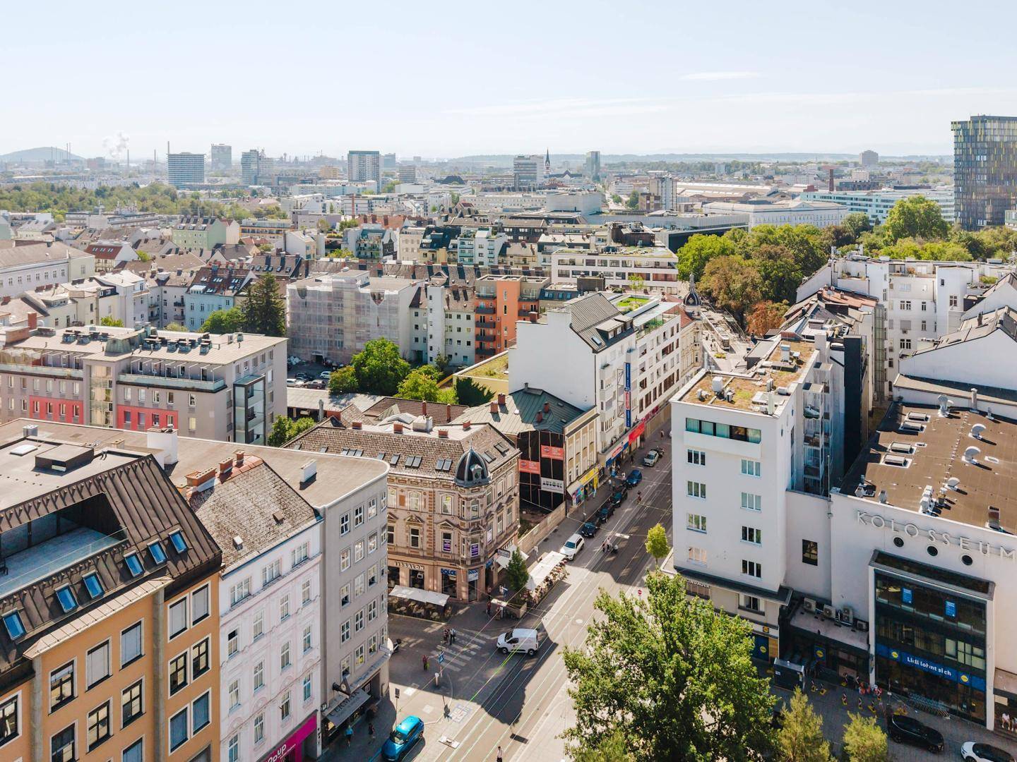 Panoramische Luftaufnahme einer Stadt mit weitem Blick über Dächer, Straßen und Industriegebiete am Horizont.