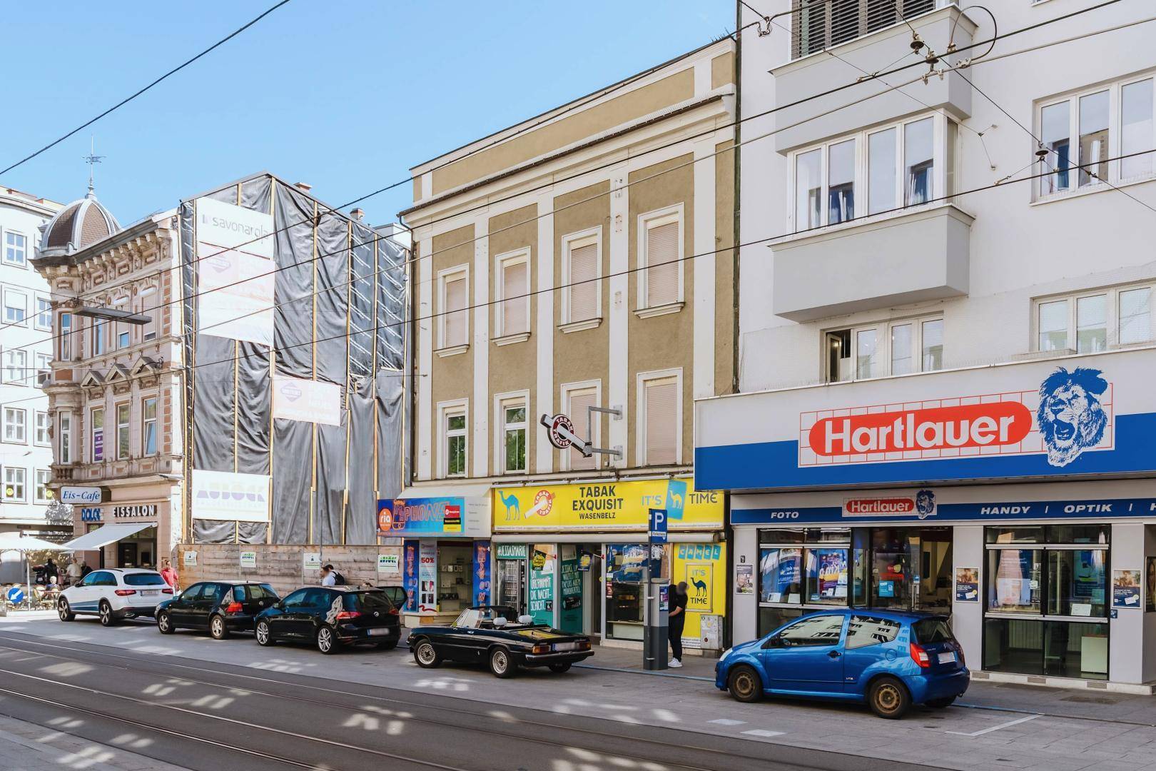Eine Reihe von Geschäftsgebäuden entlang einer Stadtstraße, einige davon mit Gerüsten für Renovierungsarbeiten.
