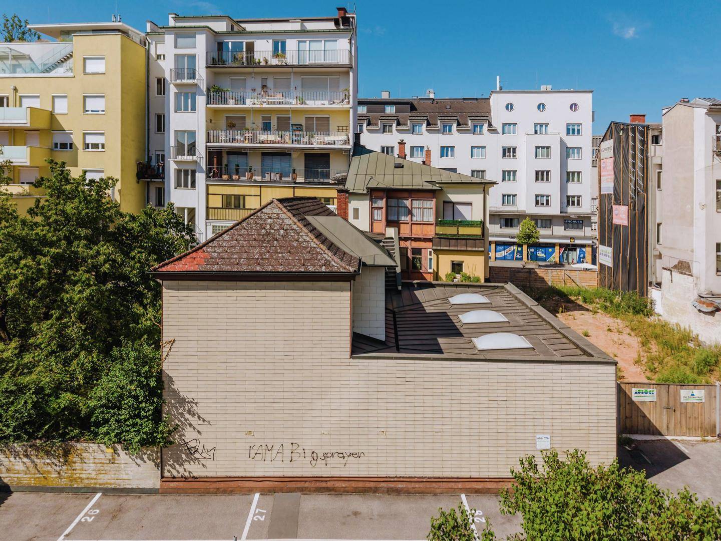 Rückansicht eines älteren Gebäudes mit einer Garage und mehreren Parkplätzen im Freien.