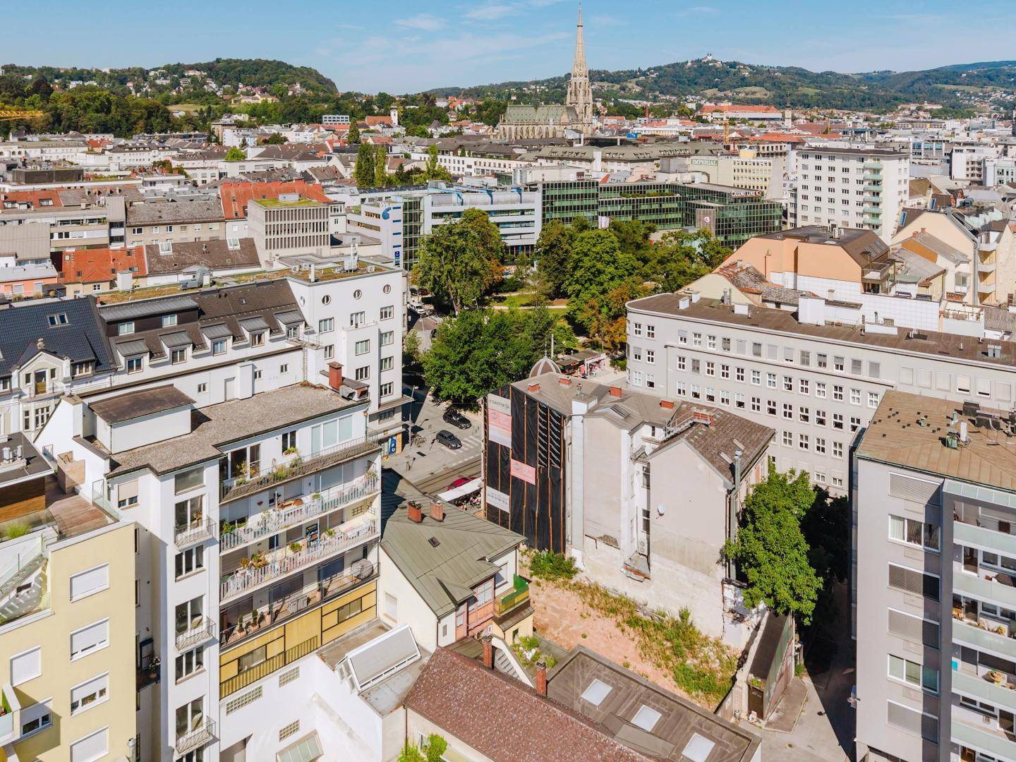 Weitläufige Luftaufnahme einer Stadt mit unterschiedlichen Gebäudetypen, Straßen und Grünflächen.