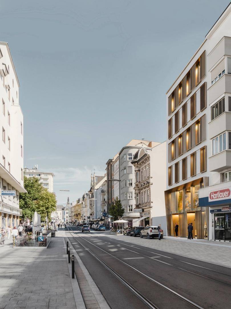 Eine breite Stadtstraße mit modernen und traditionellen Gebäuden, Geschäften und parkenden Autos.
