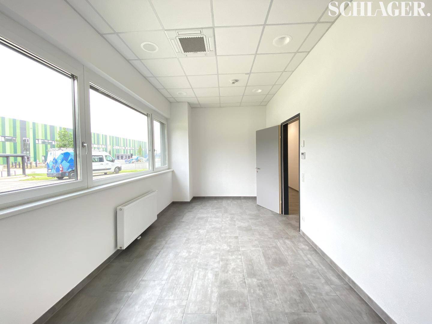Heller Flur oder Empfangsbereich mit Fliesenboden, abgehängter Decke und großen Fenstern, die viel Licht spenden.