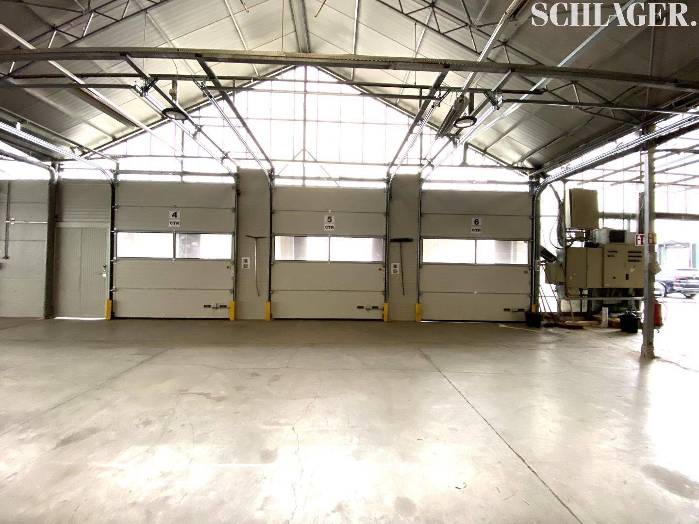Ladebereich einer Industriehalle mit drei großen Rolltoren, hoher Decke und robustem Betonboden für effiziente Logistik.