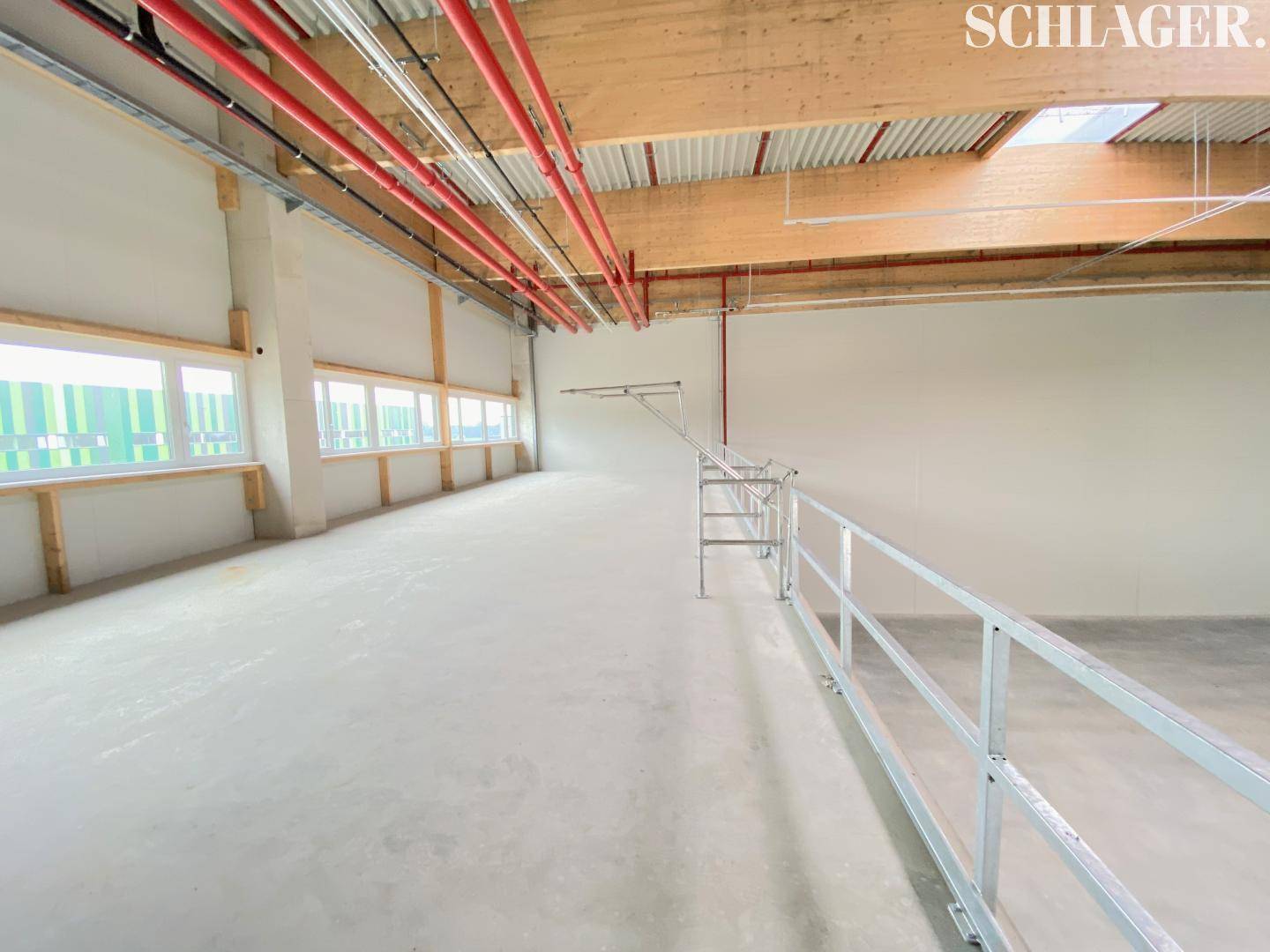 Mezzanine-Ebene in der Lagerhalle mit Blick auf die Deckenkonstruktion, Fensterfront und Brandschutzrohre.
