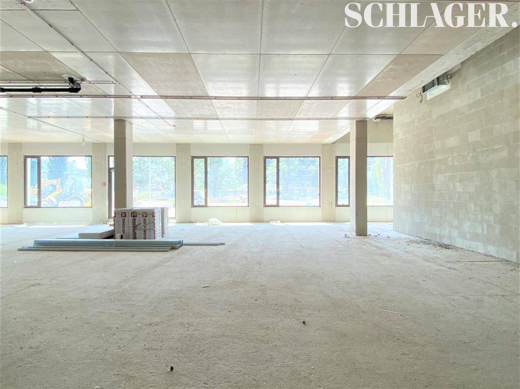 Geräumiger Gewerberaum im Rohbau mit großen Fenstern und Betonwänden, bereit für den Innenausbau.