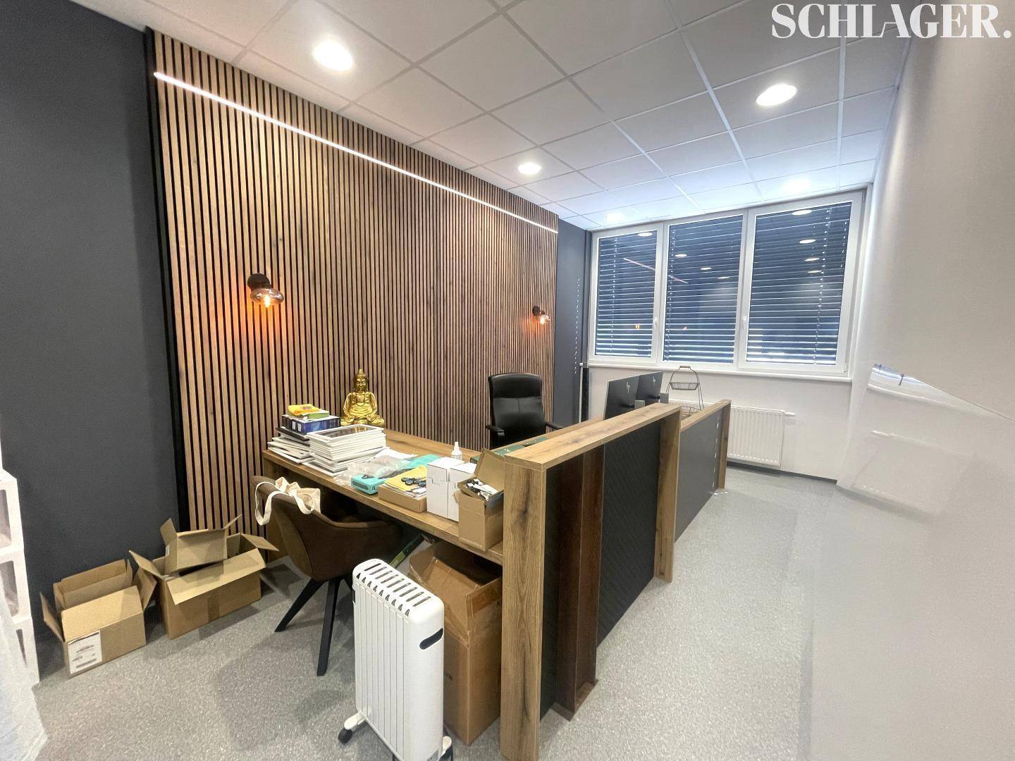 Modernes Büro mit stilvoller Holzlamellenwand, großem Schreibtisch und natürlichem Lichteinfall durch das Fenster.