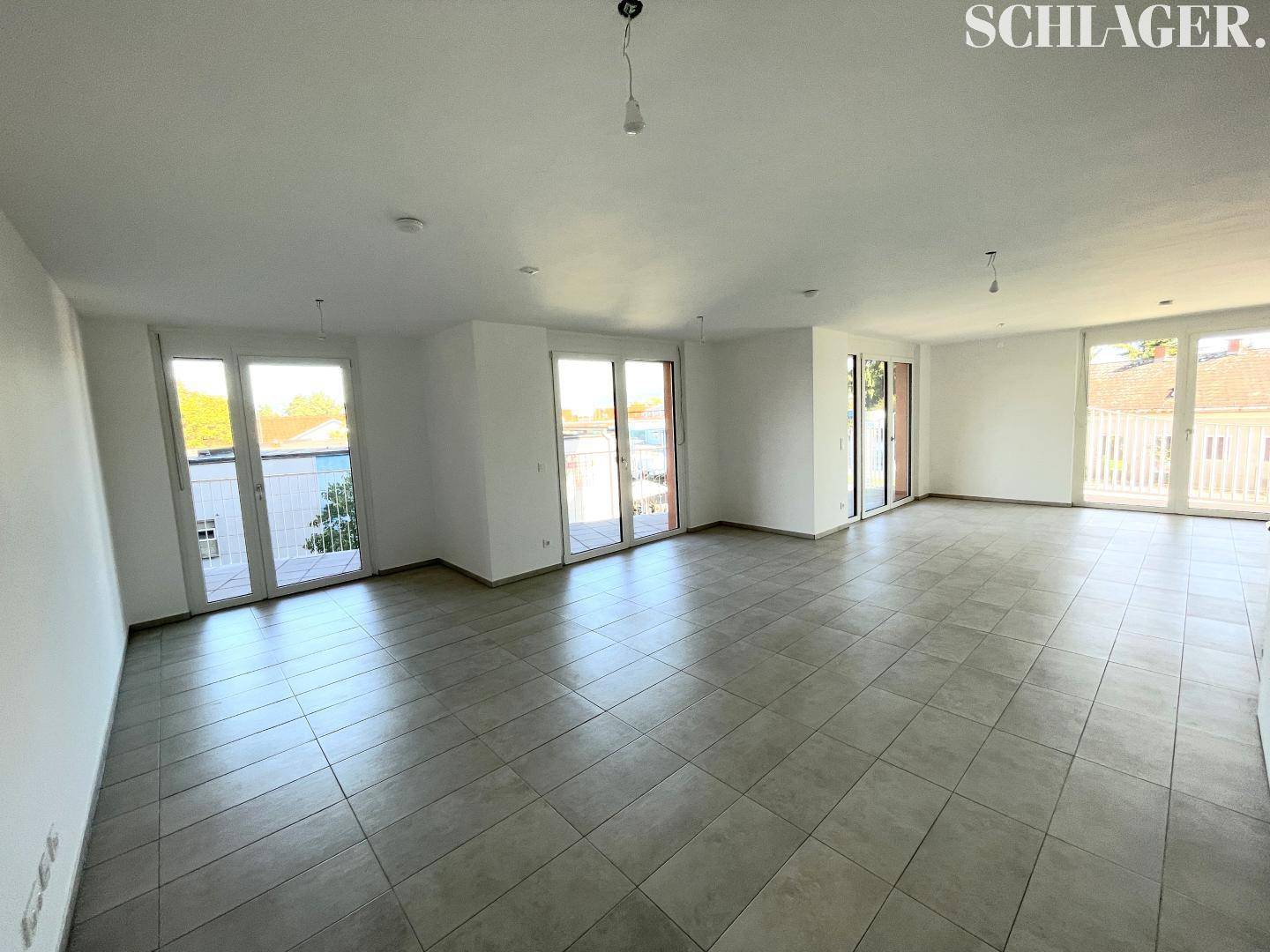 Weitläufiger Wohnraum mit zahlreichen großen Fenstern, die viel Licht hereinlassen und einen weiten Blick bieten.