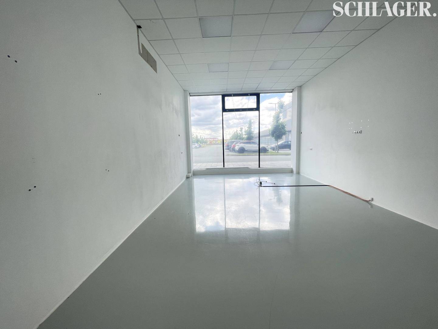 Heller, leerer Raum mit großen Fenstern, die viel Licht hereinlassen, ideal als Büro oder Empfangsbereich.