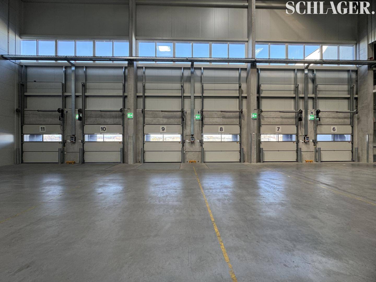 Innenansicht einer Lagerhalle mit mehreren nummerierten Rolltoren und Oberlichtern für Tageslicht.