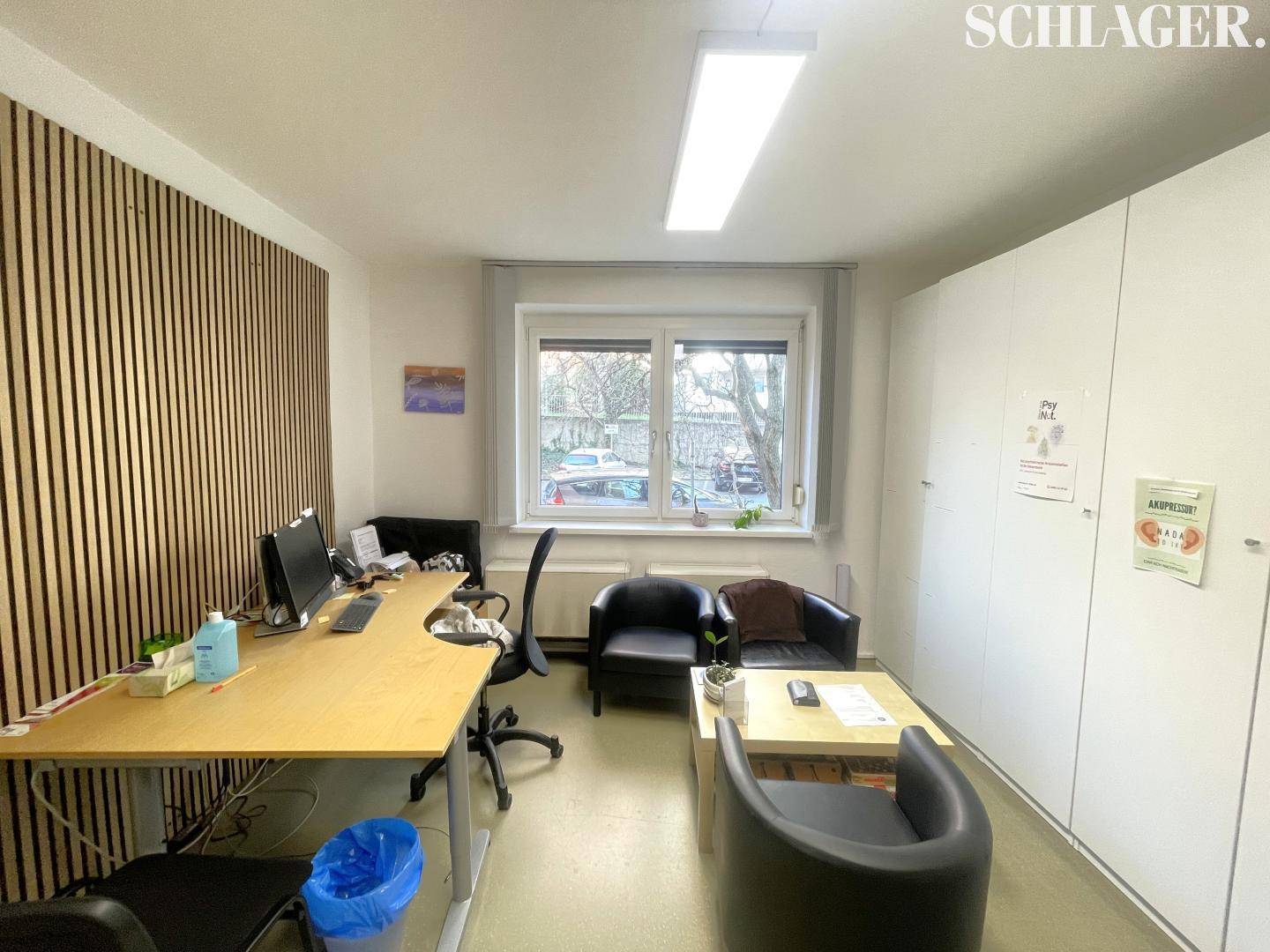 Modernes Büro mit Holzwandverkleidung, Schreibtisch, bequemen Sesseln und viel Stauraum.