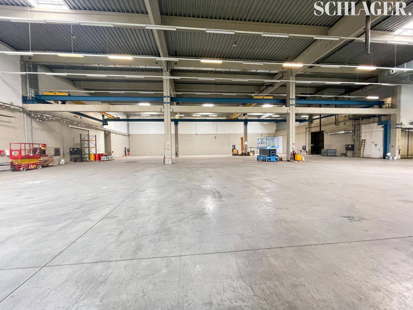 Weitläufige Lagerhalle mit Betonboden, Kranbahnen und viel Platz für Lagerung und Betrieb.