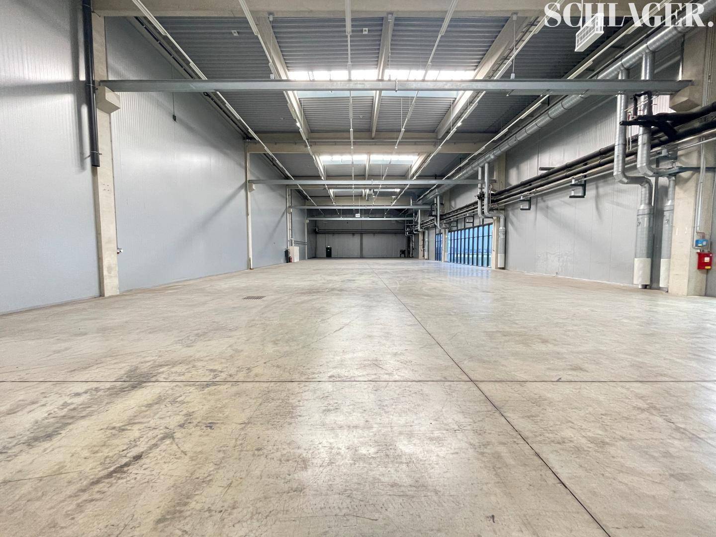 Leere Lagerhalle mit glattem Betonboden und hohen Wänden, bereit für neue Mieter.