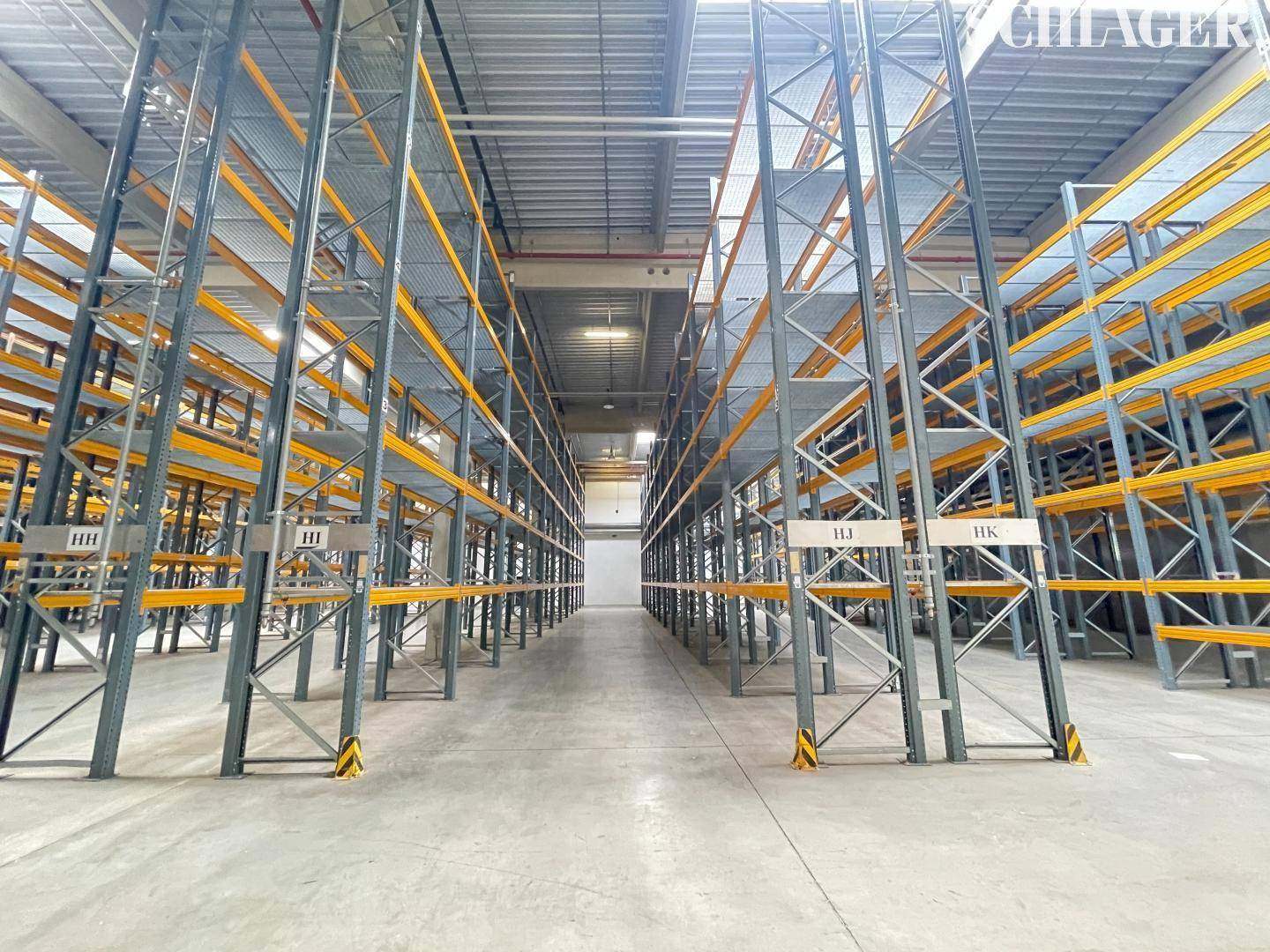 Lagerhalle mit hohen Regalsystemen und Betonboden, bereit für die Einlagerung von Waren.