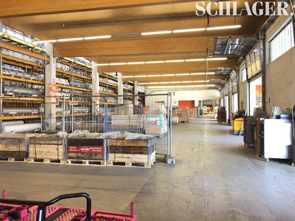 Lagerhalle mit Regalsystemen, Holzträgern und großen Fenstern für Tageslichteinfall.