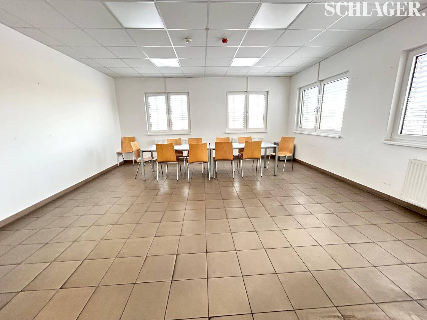 Heller Essbereich mit Fliesenboden, weißen Wänden und einem langen Tisch mit Stühlen.