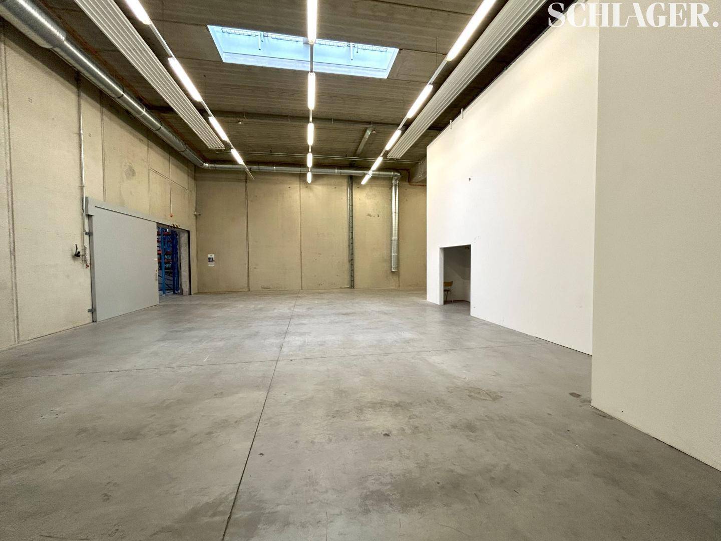 Großer, leerer Gewerberaum mit Betonwänden, Betonboden, Oberlicht und hohen Decken.