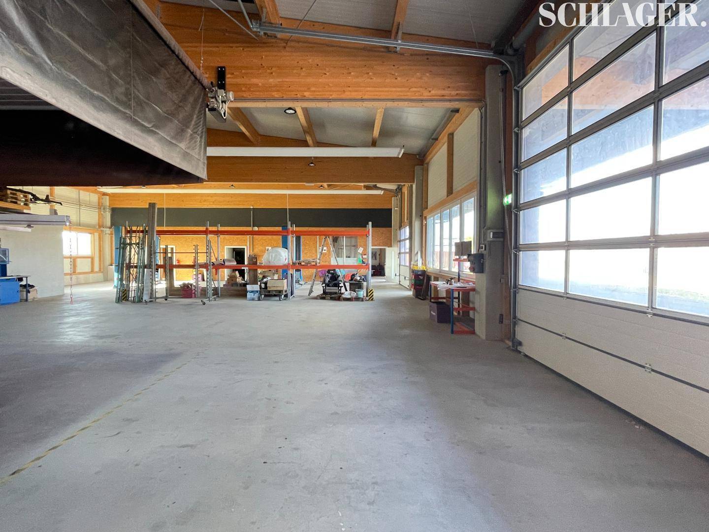 Weitläufige Werkstatthalle mit viel Platz, großen Fenstern und natürlicher Beleuchtung durch die Fenster.