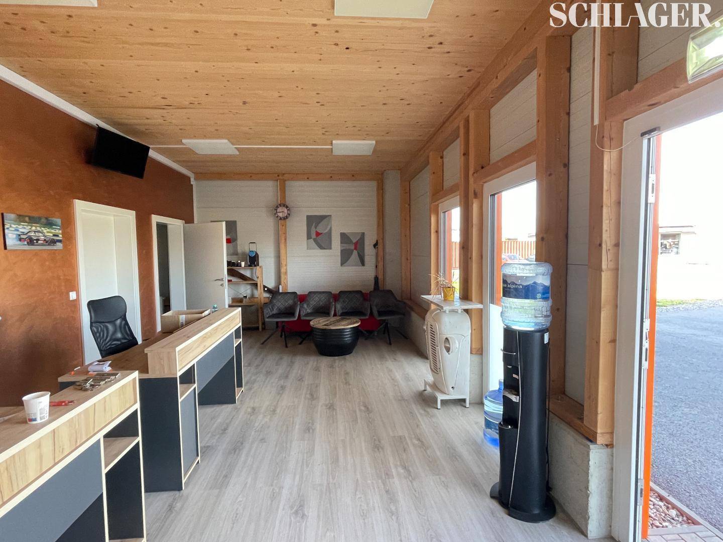 Heller Empfangsbereich mit Holzverkleidung an Wänden und Decke, einem Tresen und einer kleinen Sitzecke.
