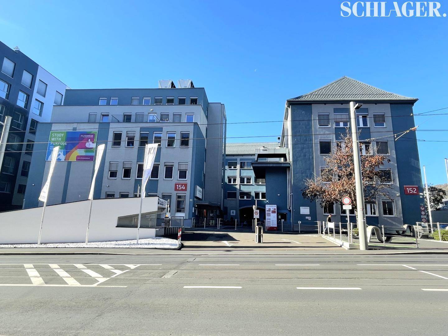 Mehrere moderne Bürogebäude mit blauer Fassade und großen Fenstern an einer Straße.