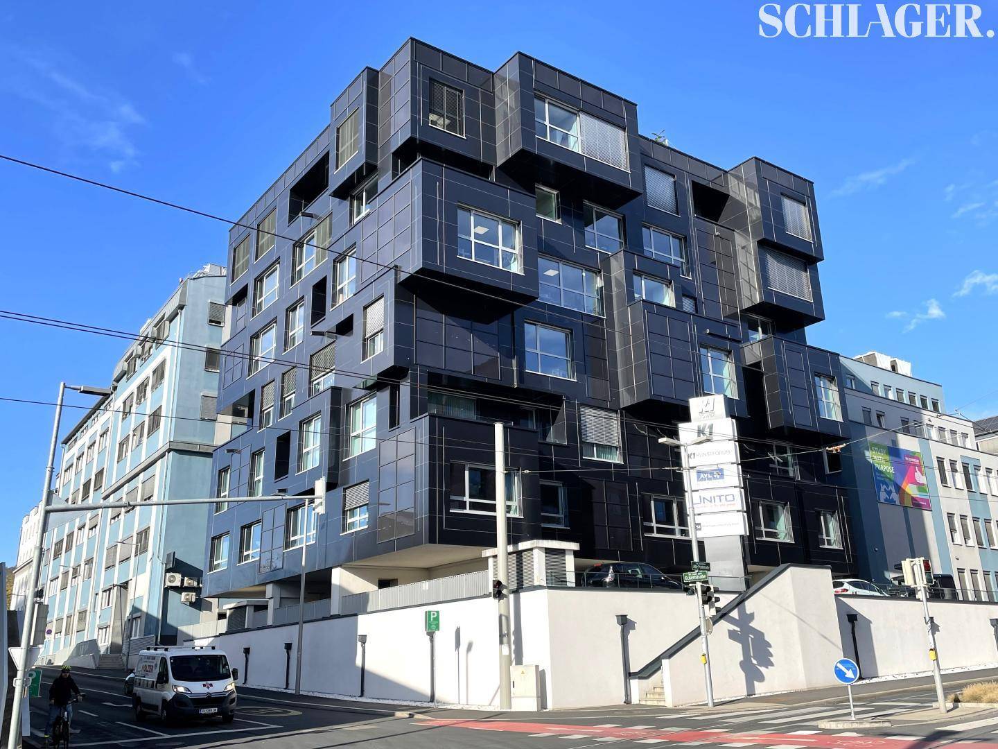 Markantes modernes Gebäude mit dunkler Fassade und vielen Fenstern, gelegen an einer belebten Straße.