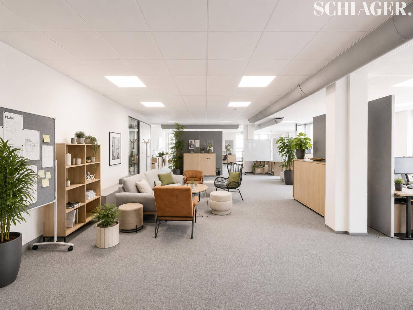 Offener Bürobereich mit verschiedenen Arbeits- und Entspannungszonen, modernen Möbeln und vielen Pflanzen.