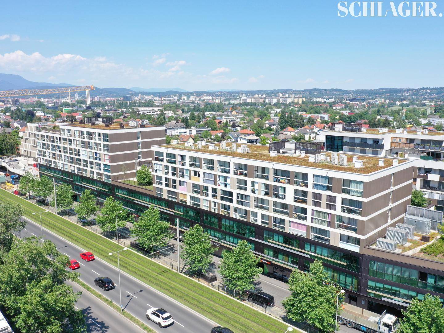 Weitläufige Ansicht des modernen Gebäudekomplexes mit begrünten Dächern und der umliegenden Stadtlandschaft.