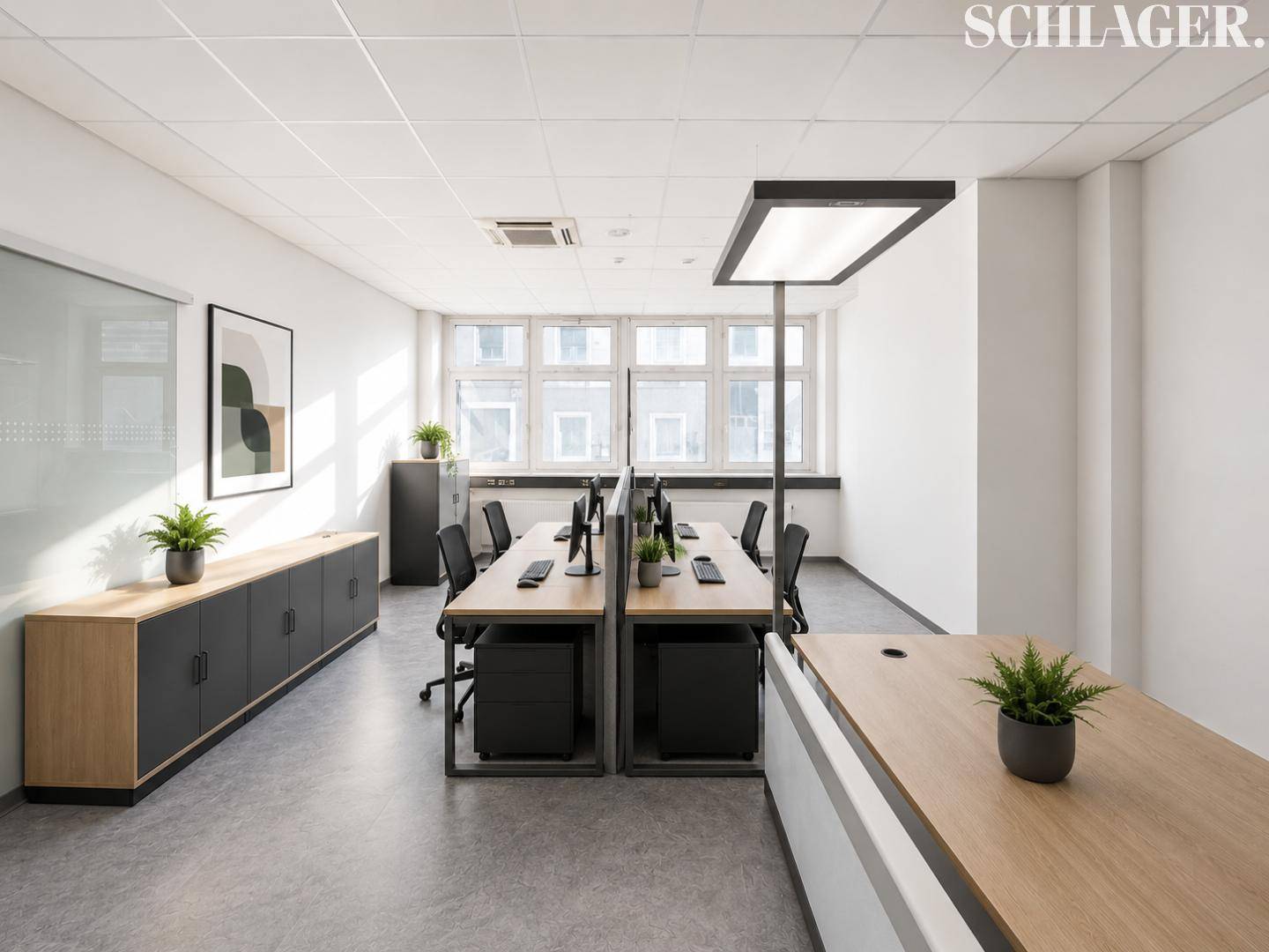 Moderner Bürobereich mit mehreren Arbeitsplätzen, Holzmöbeln und viel Tageslicht.