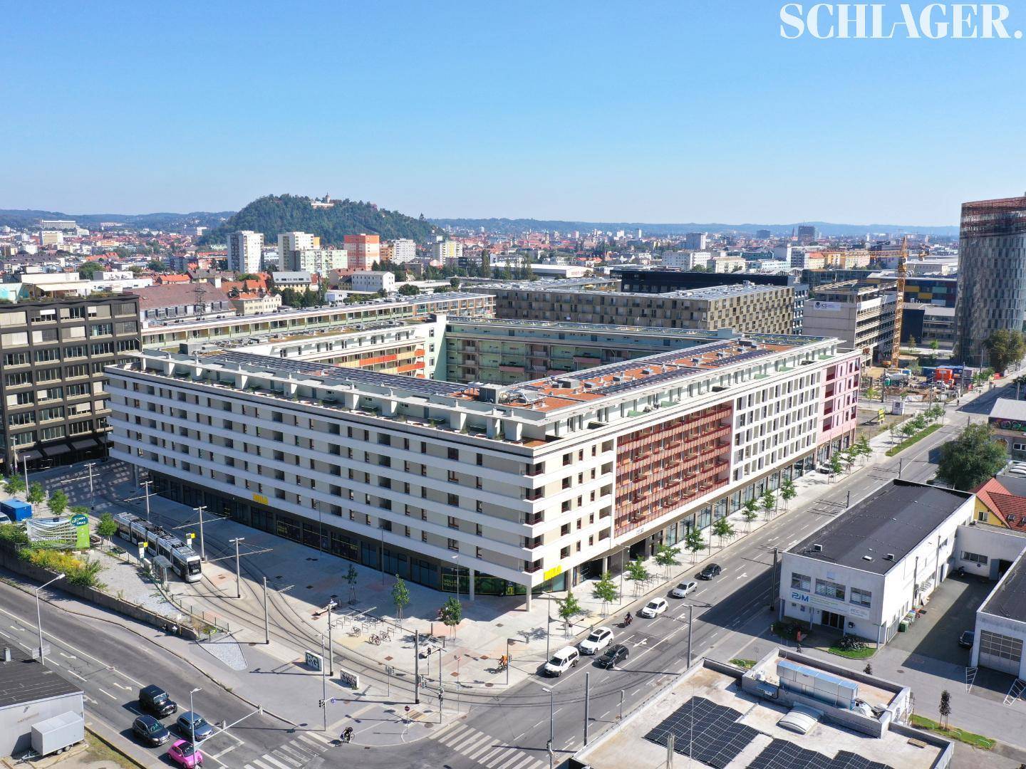Weitläufige Luftaufnahme eines modernen Gebäudekomplexes in einer städtischen Umgebung mit vielen Balkonen.