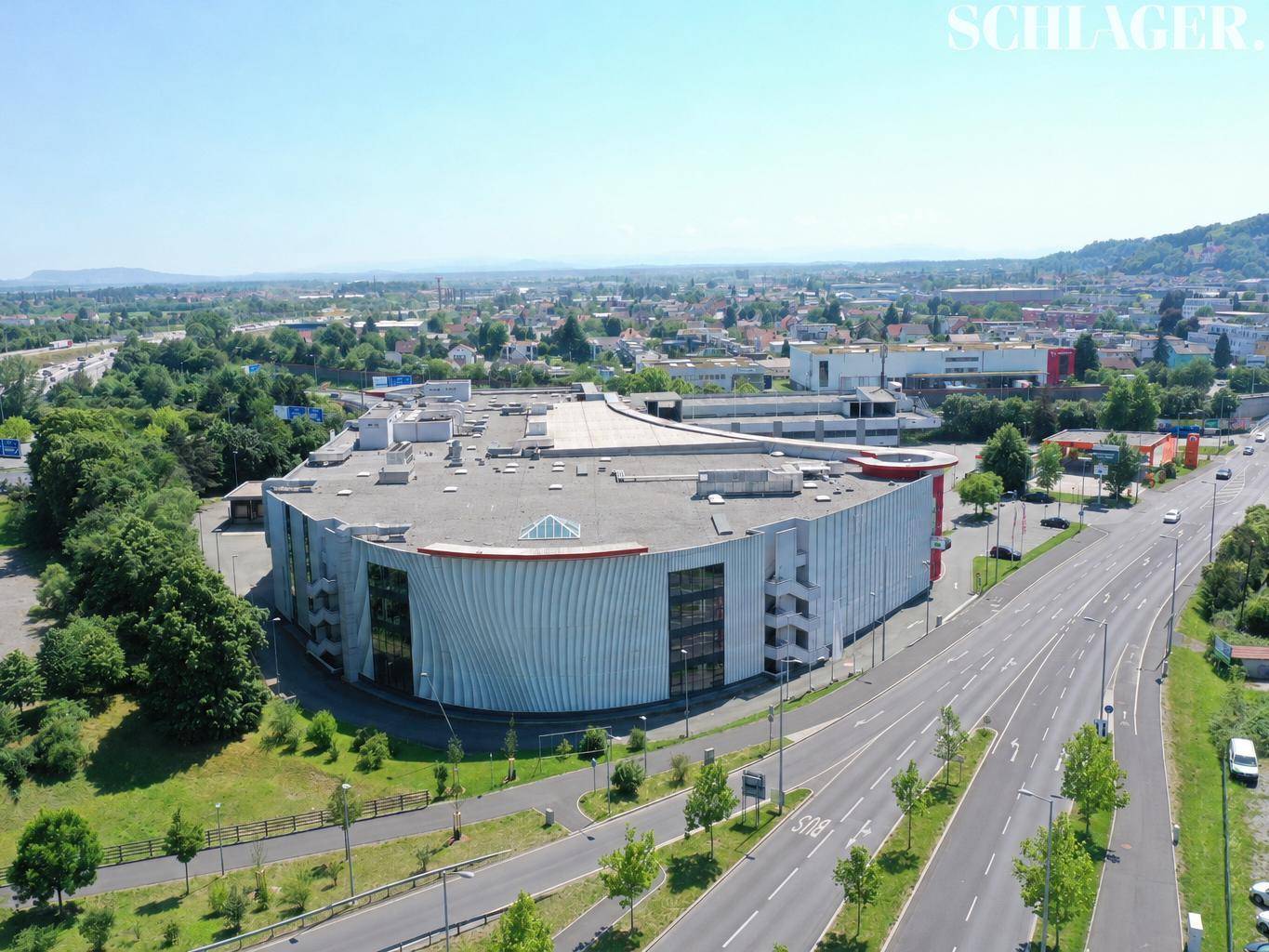 Luftaufnahme eines großen modernen Geschäftsgebäudes mit markanter Fassade und umliegenden Straßen.