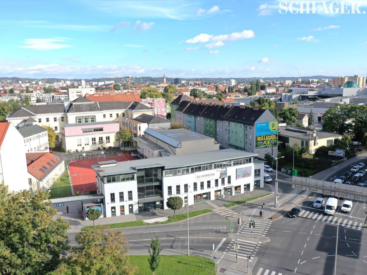 Luftaufnahme eines Geschäftsgebäudes in einer städtischen Umgebung mit umliegenden Gebäuden und Straßen.