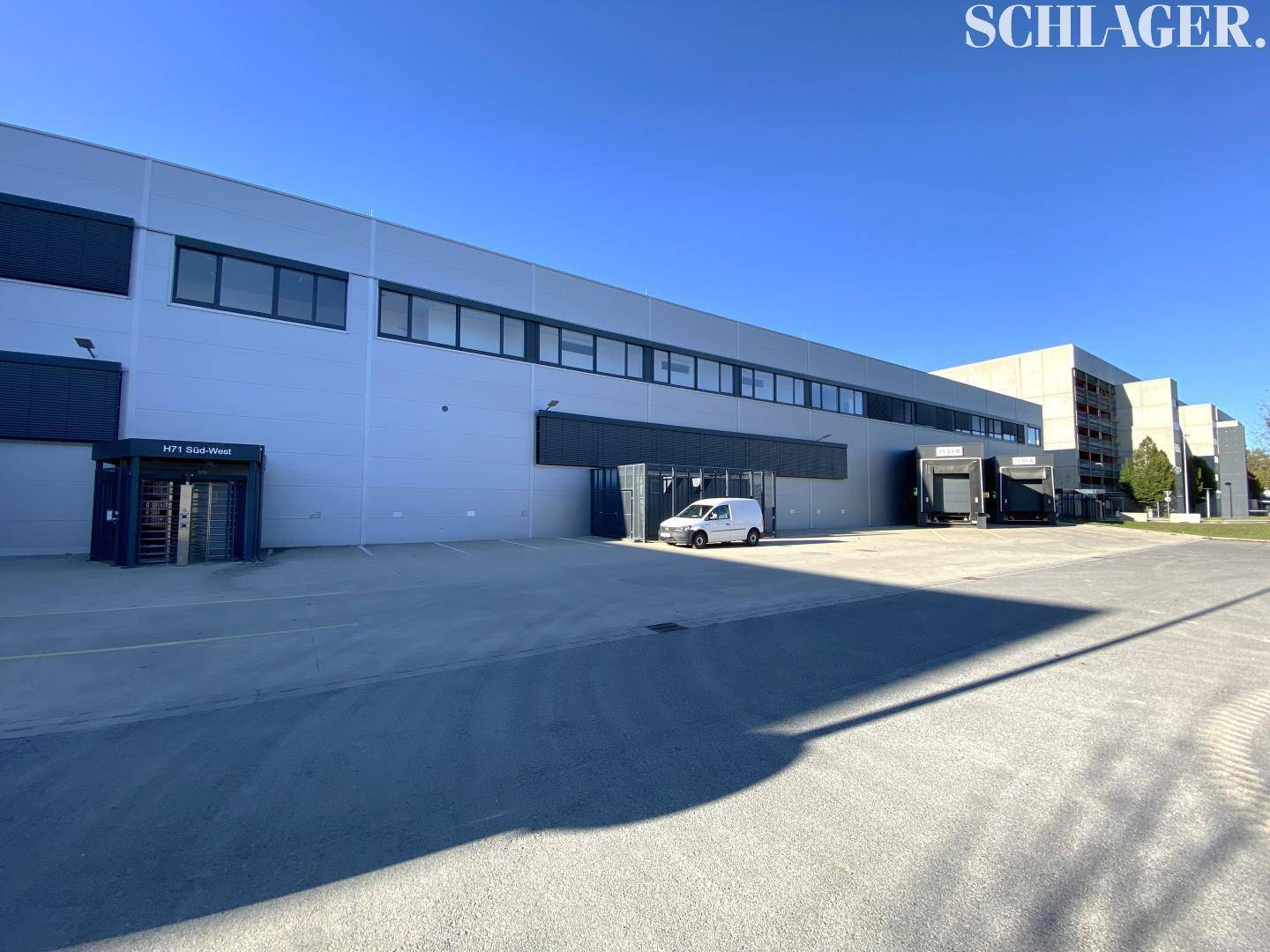 Rückseite der Industriehalle mit mehreren Laderampen und einem großen Parkplatzbereich.