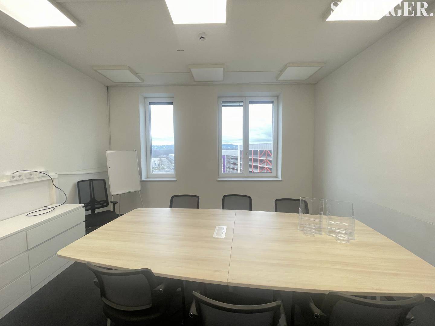 Besprechungsraum mit großem Konferenztisch, bequemen Stühlen und Fenstern mit Ausblick.
