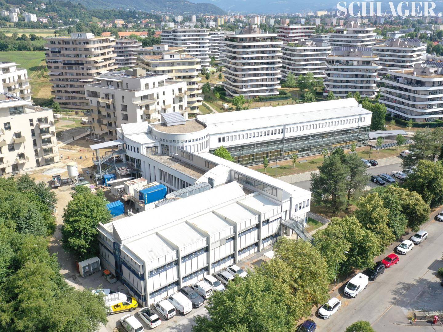 Weitläufige Luftaufnahme des modernen Gebäudekomplexes, umgeben von weiteren Wohngebäuden und viel Grün.